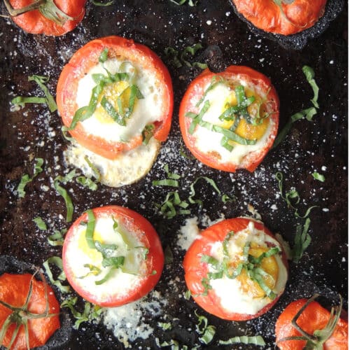 Overhead view of four baked tomato breakfast cups topped with freshly grated Parmesan cheese and fresh basil.