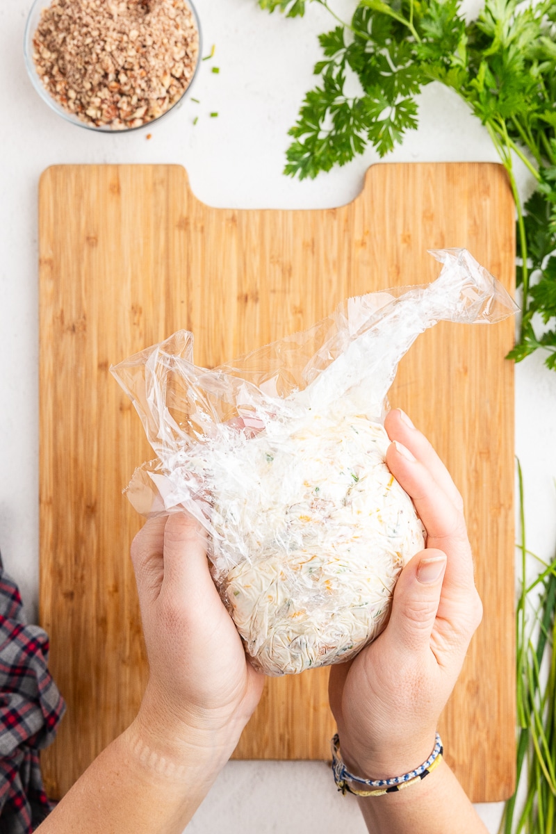 Wrapping the cheeseball in plastic wrap.