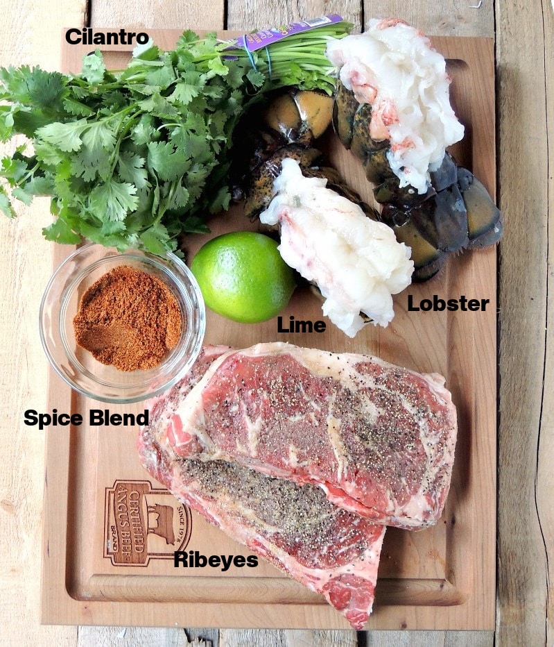 Overhead view of all of the ingredients needed to make Grilled Mexican Style Surf and Turf on a wooden cutting board on a wooden table.