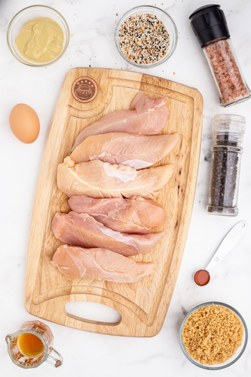 Overhead view of all of the ingredients neccessary to make Everything Bagel Chicken Tenders on a white marble counter.