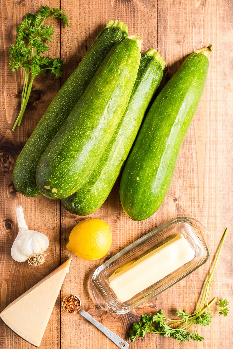 Overhead view of all of the ingredients needed to make lemon garlic zucchini noodles on a wooden table.