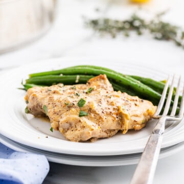 A serving of one pot dijon chicken on a white plate with green beans.