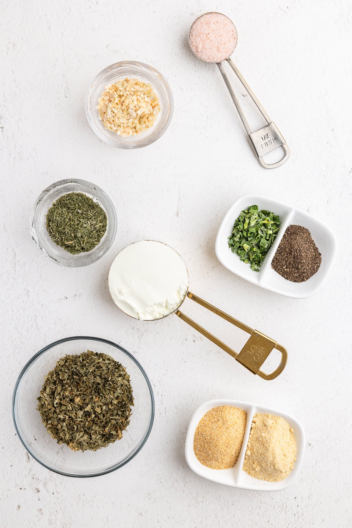 Overhead view of all of the ingredients needed to make homemade ranch seasoning mix on a white counter.