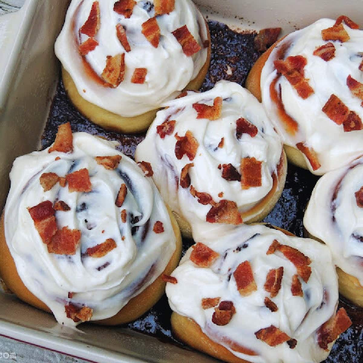 Overhead view of several sugar-free maple bacon cinnamon rolls in a baking dish.