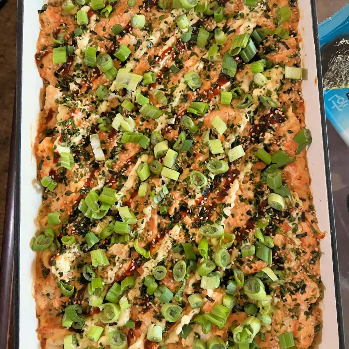 Overhead view of a shrimp and salmon sushi bake in a cream enameled cast iron casserole dish.
