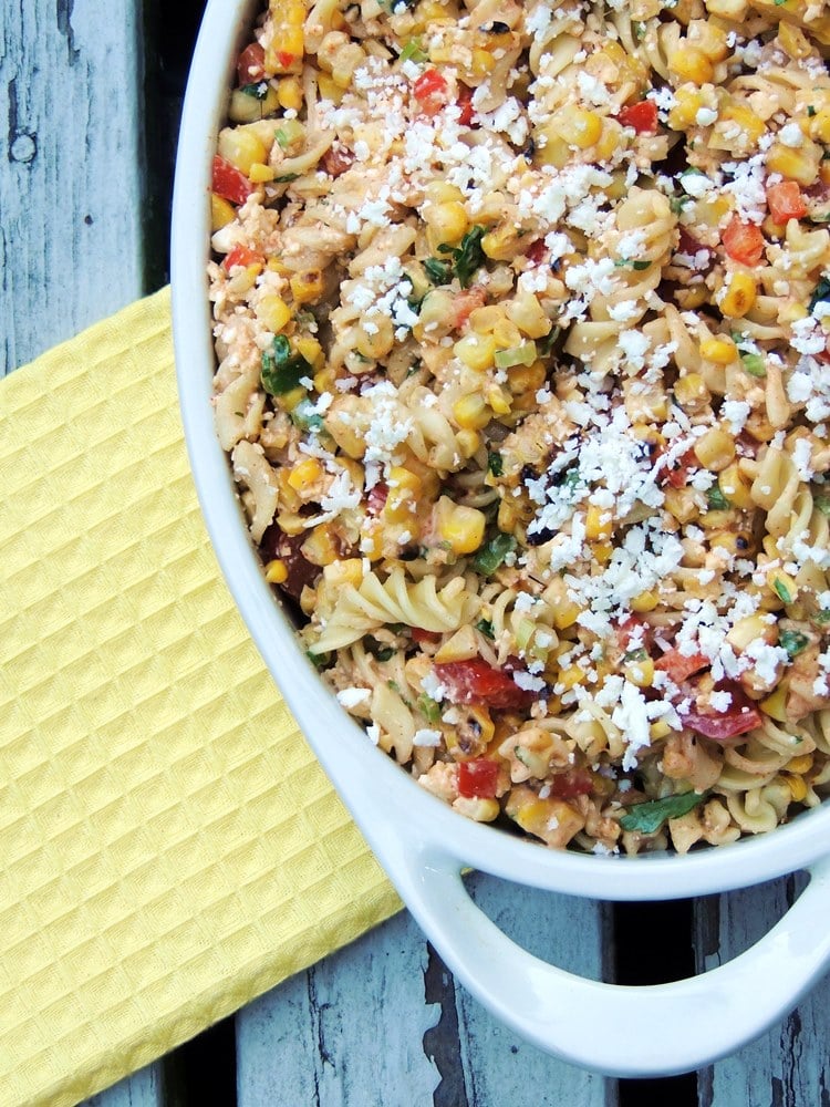 Overhead view of the bottom left corner of a white oval serving dish full of Elote Pasta Salad.
