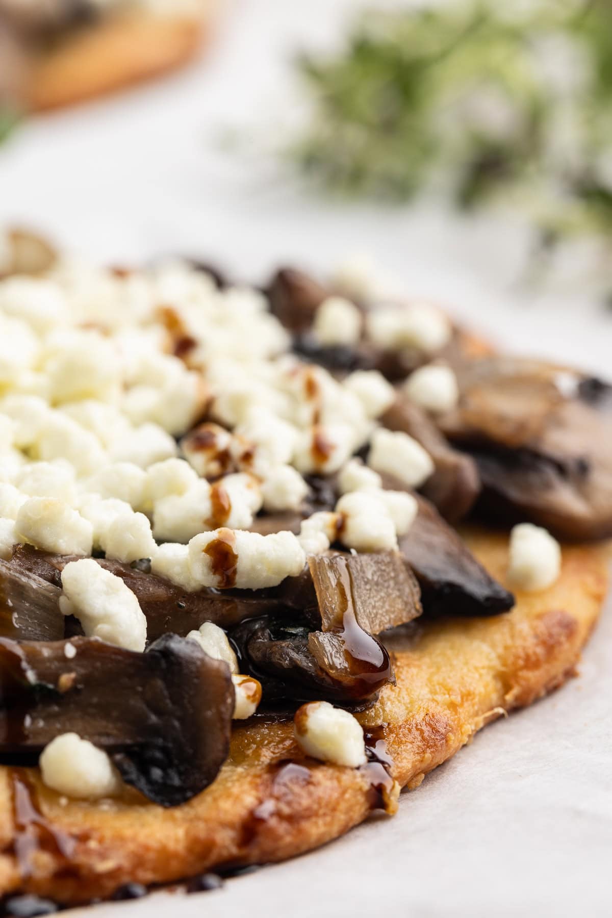 Close up view of a low-carb mushroom goat cheese flatbread drizzled with balsamic glaze.
