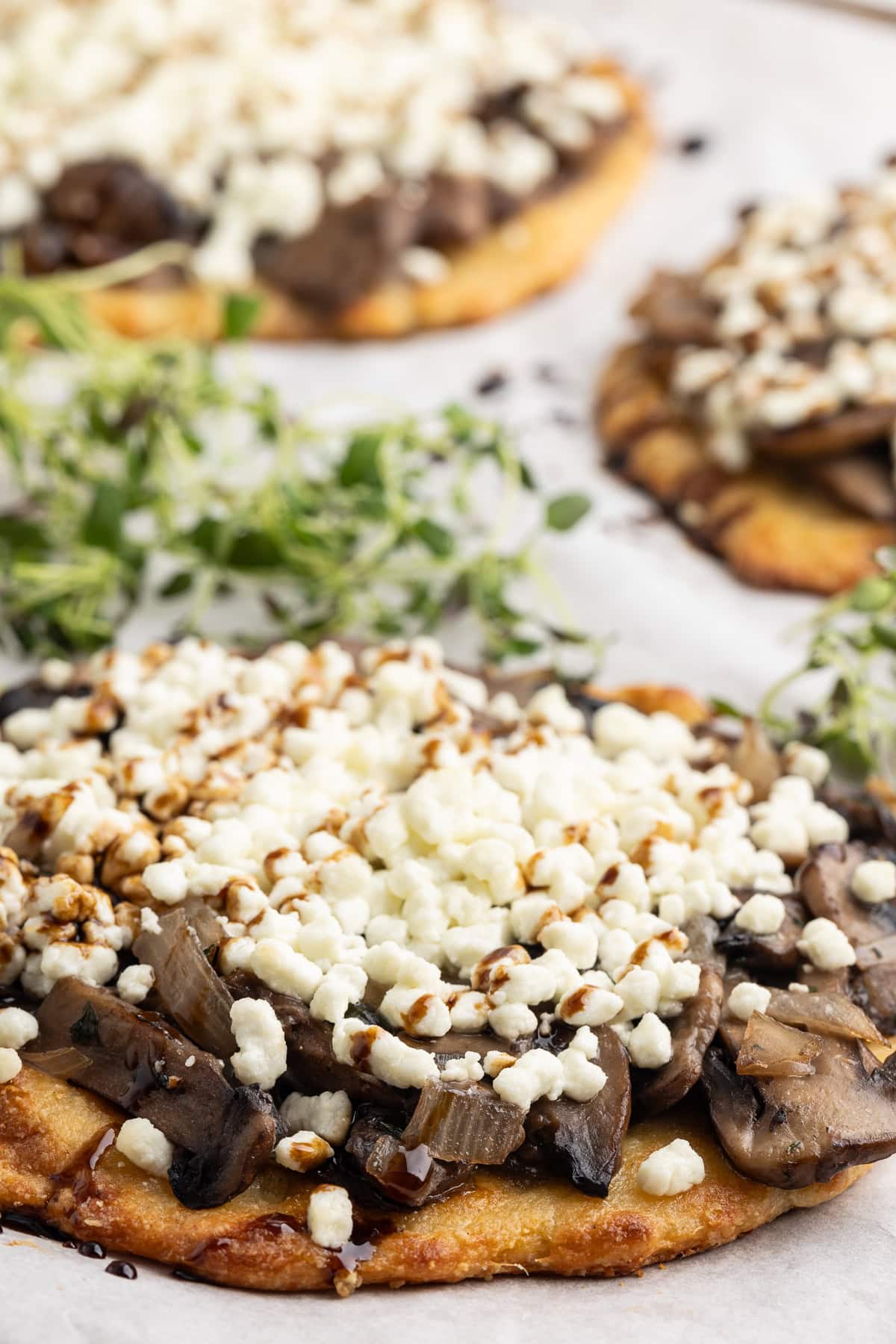 Several keto flatbreads topped with mushrooms and goat cheese.