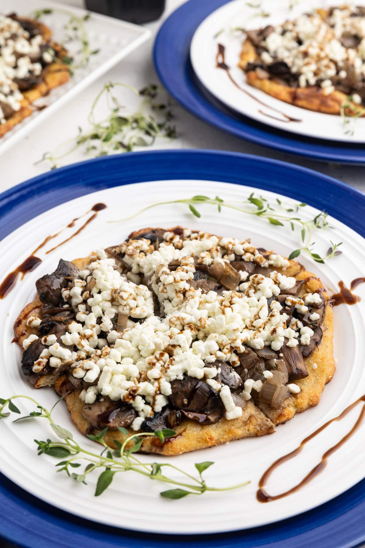 A low-carb mushroom goat cheese flatbread cut into four pieces on a white dinner plate.